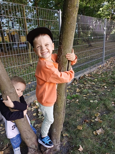 Chłopiec przytula się do drzewa.