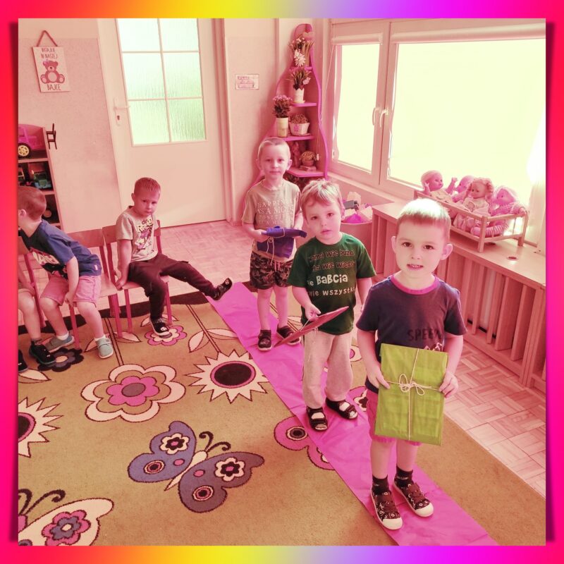 Chłopcy stoją na czerwonym dywanie z otrzymanymi prezentami.