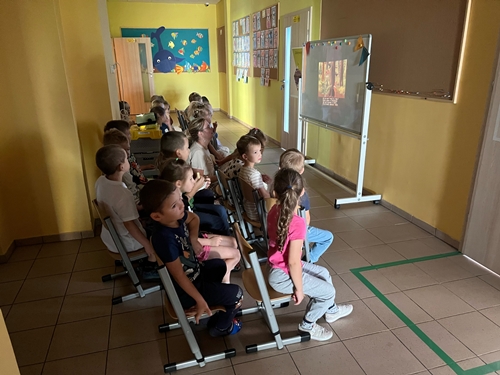 Dzieci oglądają wyświetlaną bajkę z projektora na holu przedszkola.