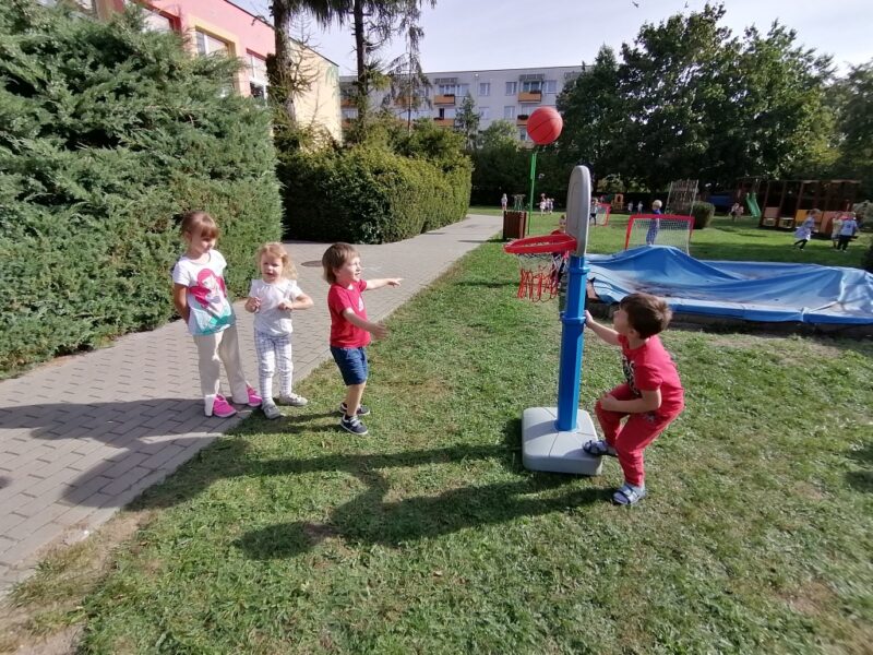 Grupka dzieci gra w koszykówkę.