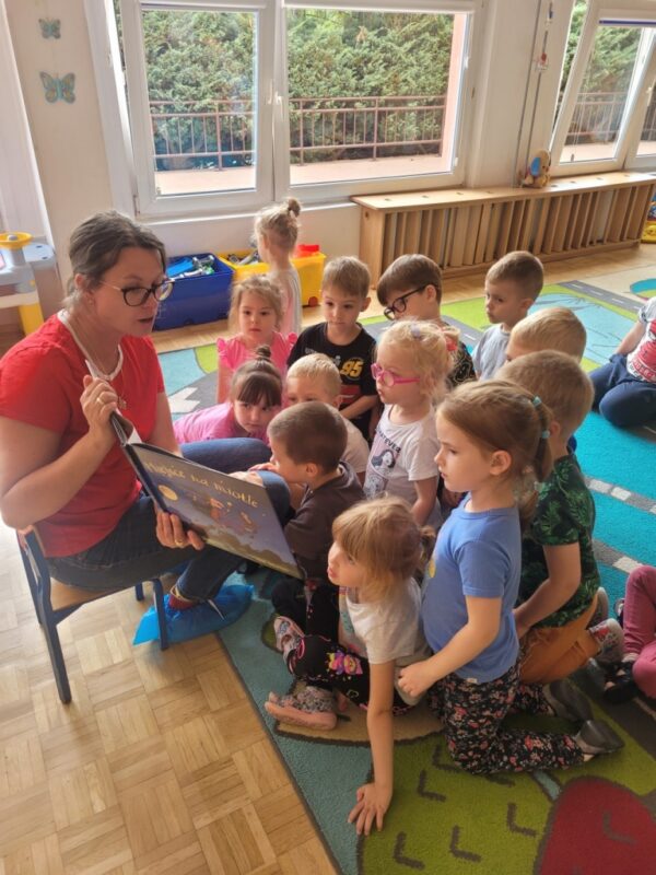 Zdjęcie przedstawia dzieci słuchające czytanej bajki.