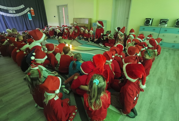 Dzieci z całego przedszkola siedzą w kręgu i uważnie słuchają listu od Świętego Mikołaja