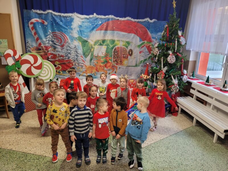 Zdjęcie grupowe "Podróżników" na tle dekoracji świątecznej w holu przedszkola.