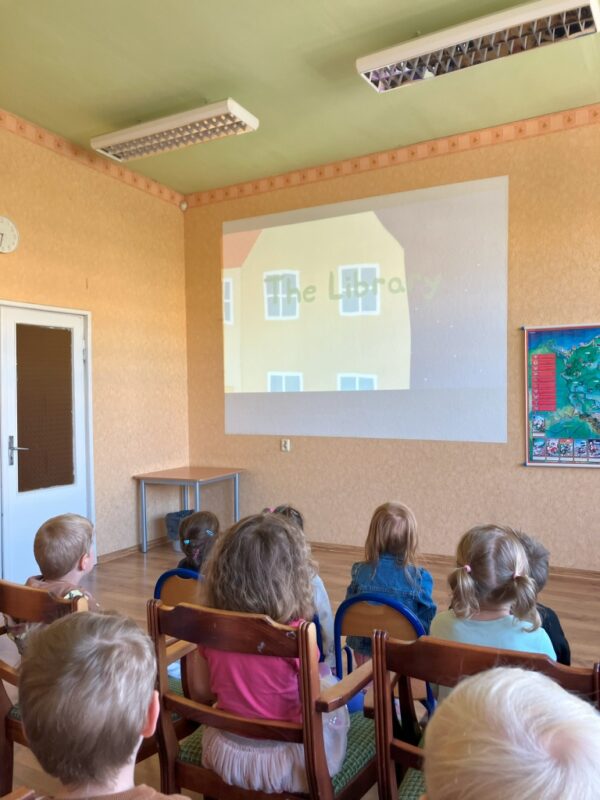 Dzieci oglądają film edukacyjny pod tytułem "Biblioteka" z serii o Śwince Pepie.